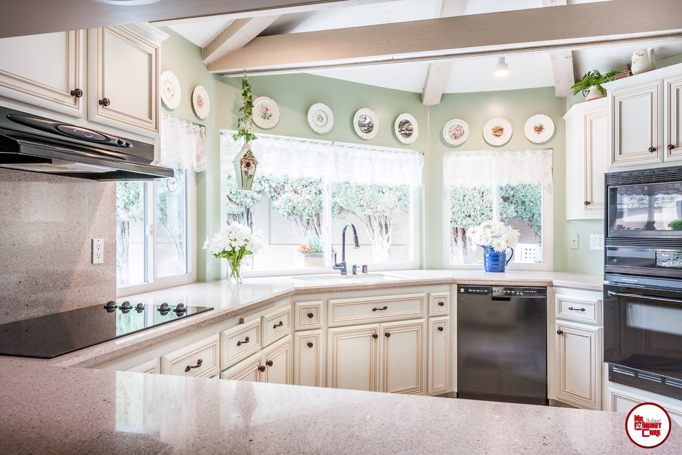 Example of a mid-sized classic u-shaped ceramic tile enclosed kitchen design in Orange County with an undermount sink, raised-panel cabinets, white cabinets, quartz countertops, multicolored backsplash, black appliances and no island