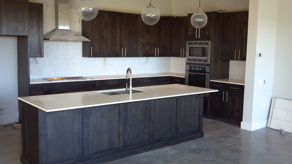 Bild på ett kök, med en dubbel diskho, luckor med infälld panel, skåp i mörkt trä, granitbänkskiva, beige stänkskydd, stänkskydd i mosaik, rostfria vitvaror, linoleumgolv och en köksö