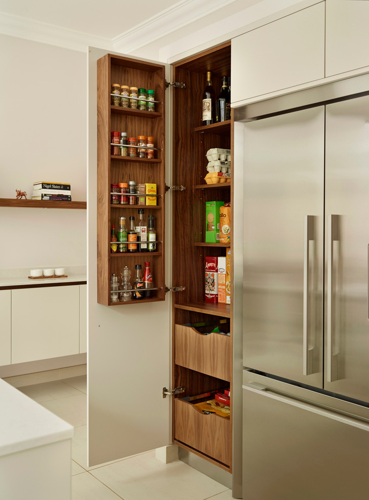 Example of a large trendy kitchen pantry design in London with flat-panel cabinets, white cabinets and stainless steel appliances