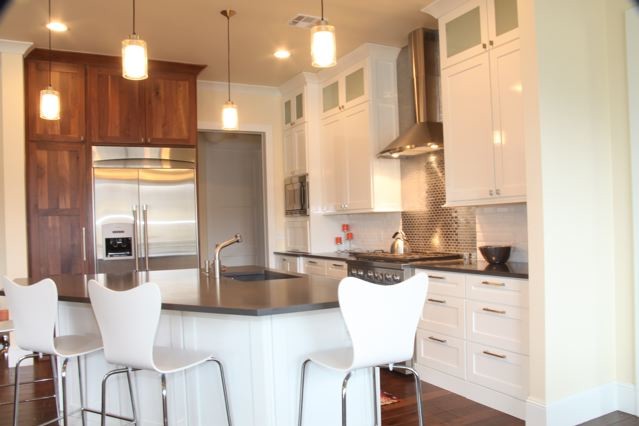 Example of a mid-sized eclectic single-wall medium tone wood floor and brown floor kitchen design in Oklahoma City with an undermount sink, shaker cabinets, white cabinets, white backsplash, subway tile backsplash, stainless steel appliances and an island