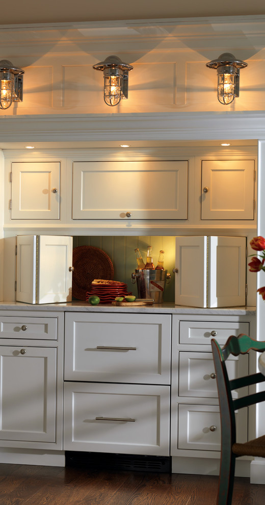 Inredning av ett maritimt mellanstort u-kök, med en rustik diskho, luckor med infälld panel, vita skåp, marmorbänkskiva, stänkskydd i porslinskakel, vita vitvaror, mörkt trägolv och en köksö