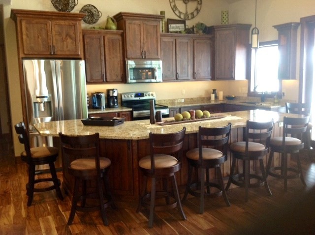Large rustic l-shaped kitchen/diner in Cedar Rapids with flat-panel cabinets, medium wood cabinets and an island.