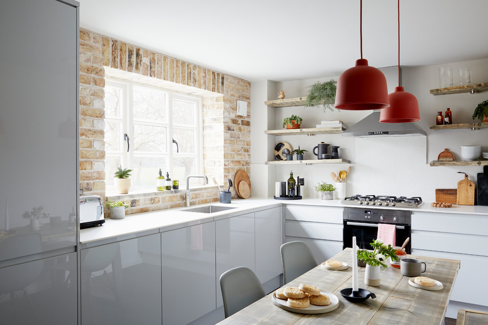Пример оригинального дизайна: угловая кухня в современном стиле с техникой из нержавеющей стали, обеденным столом, одинарной мойкой, белой столешницей, серыми фасадами, столешницей из акрилового камня и мойкой у окна