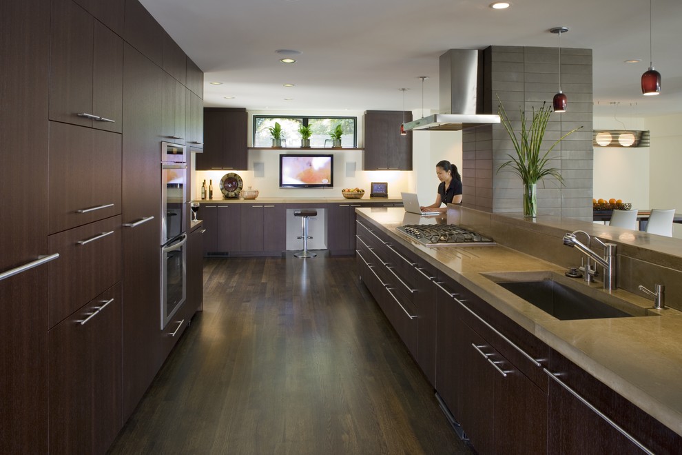 Foto på ett funkis kök och matrum, med rostfria vitvaror, en undermonterad diskho, släta luckor, skåp i mörkt trä och bänkskiva i betong