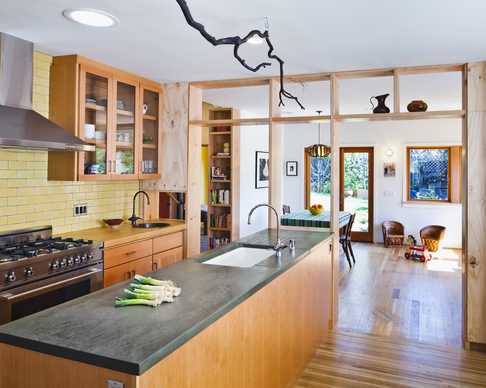 サンフランシスコにあるコンテンポラリースタイルのおしゃれなキッチン (ガラス扉のキャビネット、コンクリートカウンター、シルバーの調理設備、シングルシンク、中間色木目調キャビネット、黄色いキッチンパネル、サブウェイタイルのキッチンパネル) の写真