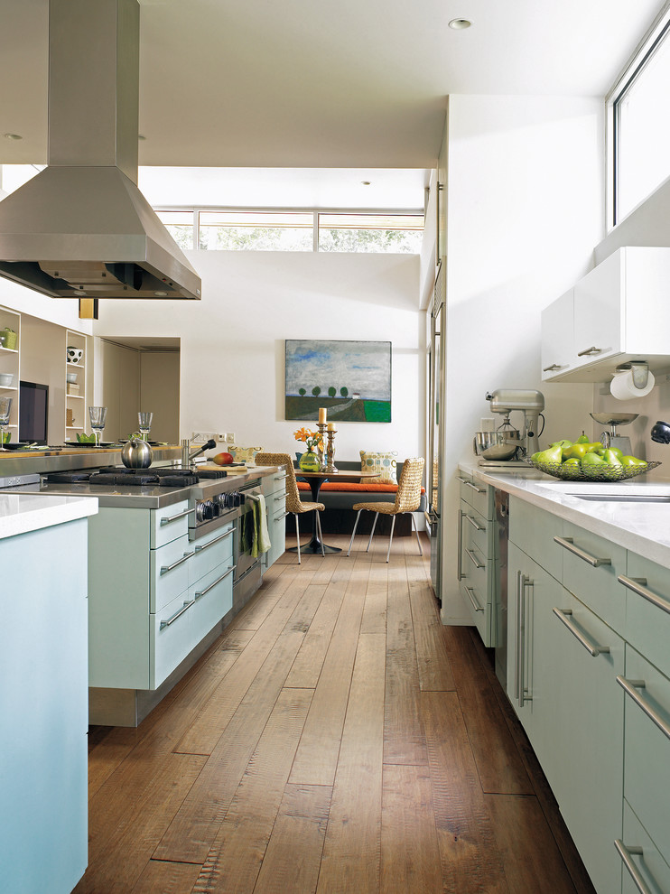 Foto på ett stort funkis kök, med en undermonterad diskho, släta luckor, blå skåp, bänkskiva i kvartsit, vitt stänkskydd, rostfria vitvaror, mellanmörkt trägolv och en köksö