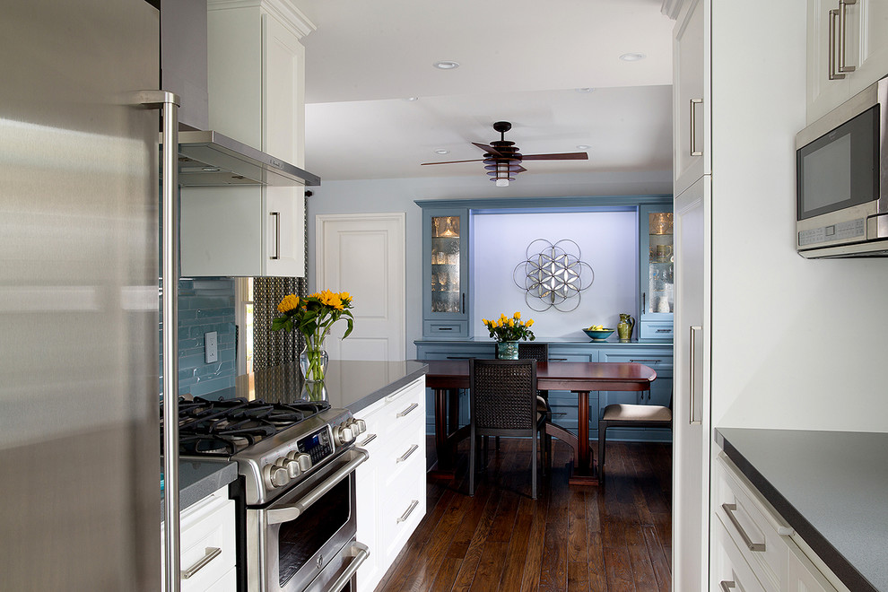 Mid-sized elegant galley dark wood floor open concept kitchen photo in Los Angeles with a farmhouse sink, shaker cabinets, white cabinets, quartz countertops, blue backsplash, glass tile backsplash, stainless steel appliances and no island