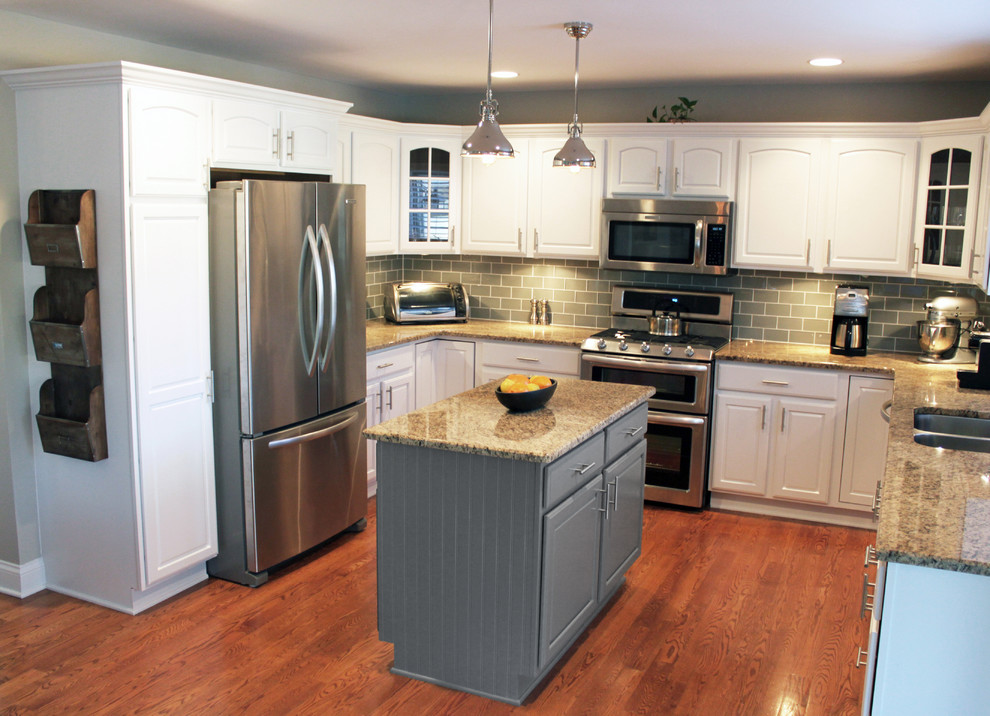 Mid-sized transitional u-shaped medium tone wood floor eat-in kitchen photo in Chicago with an undermount sink, recessed-panel cabinets, white cabinets, granite countertops, gray backsplash, glass tile backsplash, stainless steel appliances and an island