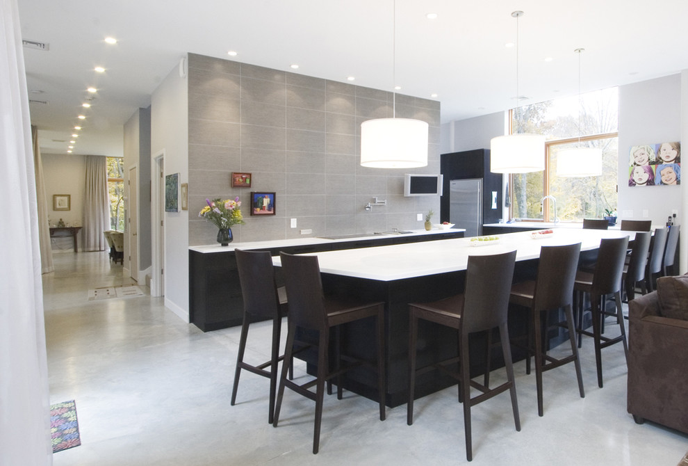 Свежая идея для дизайна: кухня-гостиная в стиле модернизм с серым фартуком, техникой из нержавеющей стали, черно-белыми фасадами и барной стойкой - отличное фото интерьера