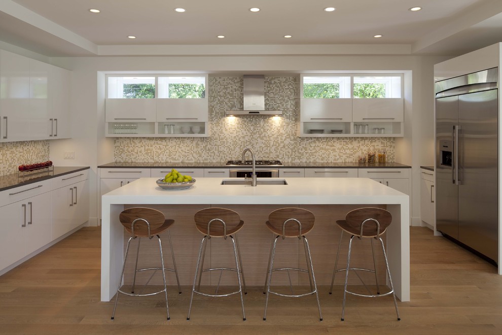 Modelo de cocina contemporánea con encimera de acrílico, fregadero de un seno, armarios con paneles lisos, puertas de armario blancas, salpicadero con mosaicos de azulejos, electrodomésticos de acero inoxidable y barras de cocina