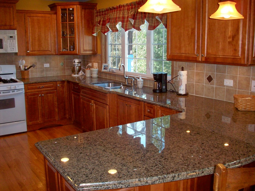 Photo of a small classic u-shaped enclosed kitchen in Chicago with a submerged sink, raised-panel cabinets, medium wood cabinets, granite worktops, beige splashback, ceramic splashback, white appliances, light hardwood flooring and a breakfast bar.