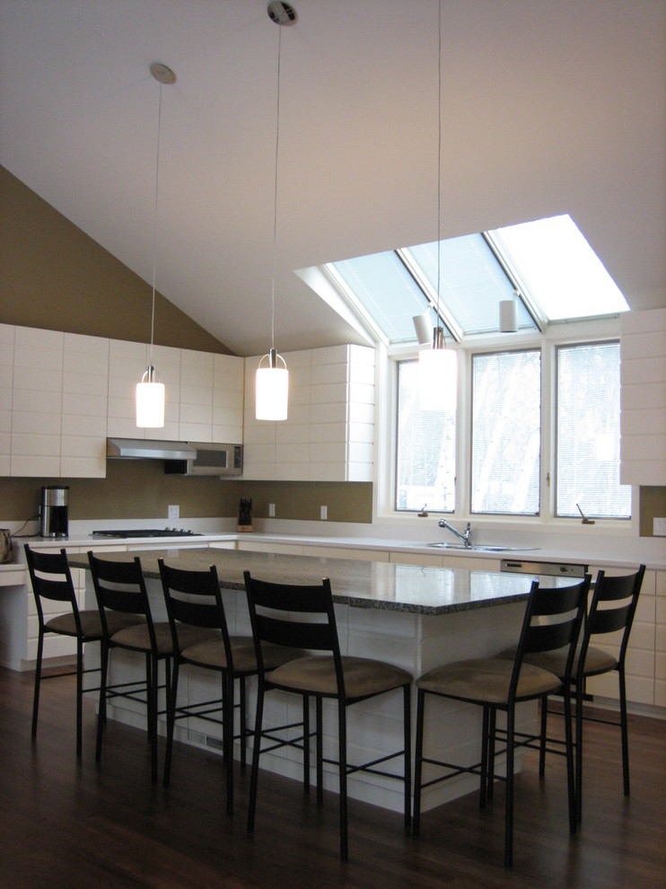 Immagine di una cucina minimalista di medie dimensioni con lavello da incasso, ante bianche, top in granito, paraspruzzi bianco, elettrodomestici in acciaio inossidabile e parquet scuro