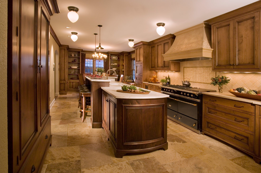 Example of a large classic galley travertine floor eat-in kitchen design in Minneapolis with an undermount sink, recessed-panel cabinets, dark wood cabinets, limestone countertops, beige backsplash, stone tile backsplash, black appliances and an island
