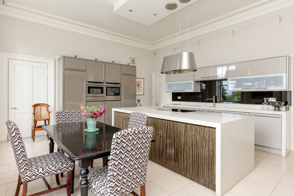Foto på ett funkis kök och matrum, med släta luckor, grå skåp, svart stänkskydd, rostfria vitvaror, en köksö och beiget golv