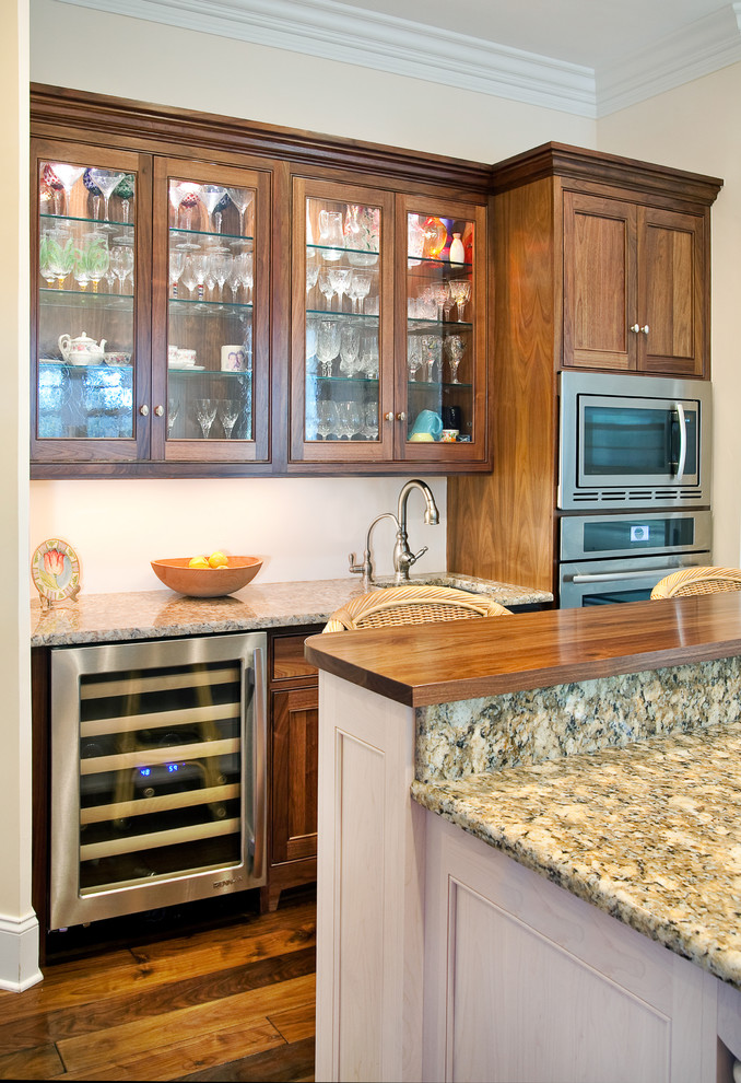 Exempel på ett mellanstort klassiskt kök, med en undermonterad diskho, luckor med glaspanel, skåp i slitet trä, granitbänkskiva, rostfria vitvaror och mellanmörkt trägolv