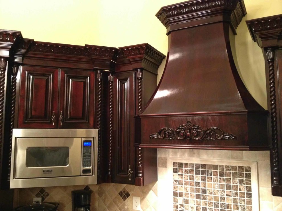 Foto de cocina contemporánea con armarios con paneles con relieve, puertas de armario de madera en tonos medios, encimera de granito, electrodomésticos de acero inoxidable y suelo marrón