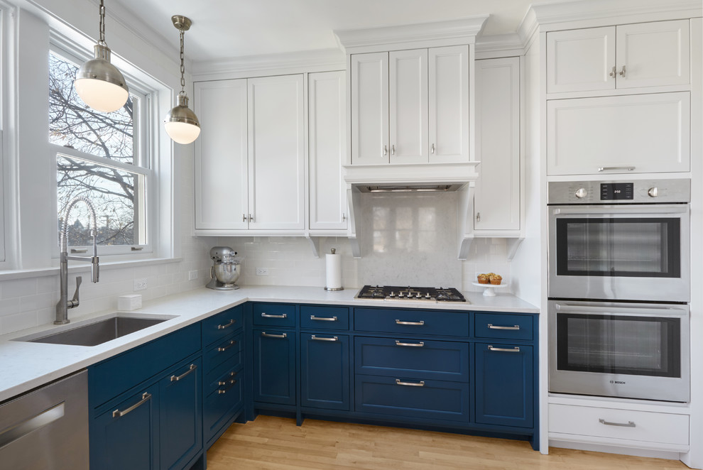 Réalisation d'une cuisine tradition en L avec un évier encastré, un placard à porte shaker, des portes de placard bleues, une crédence blanche, un électroménager en acier inoxydable et parquet clair.