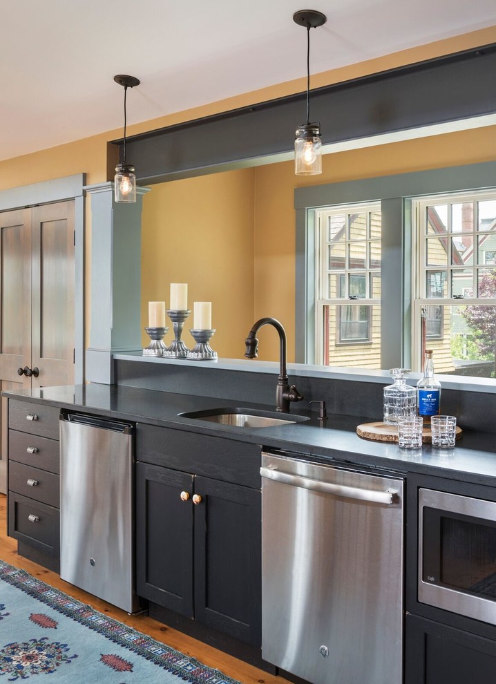 Urige Küche mit Unterbauwaschbecken, Schrankfronten im Shaker-Stil, schwarzen Schränken, Küchengeräten aus Edelstahl, braunem Holzboden und schwarzer Arbeitsplatte in Providence