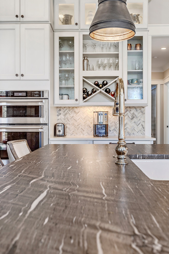 This is an example of a large country l-shaped kitchen/diner in Charleston with a belfast sink, recessed-panel cabinets, white cabinets, white splashback, mosaic tiled splashback, stainless steel appliances, dark hardwood flooring, an island, brown floors and brown worktops.