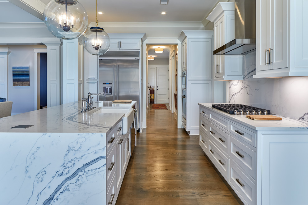 Large beach style l-shaped medium tone wood floor and brown floor eat-in kitchen photo in Charleston with a farmhouse sink, white cabinets, white backsplash, stainless steel appliances, an island, white countertops and beaded inset cabinets
