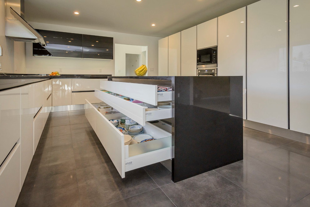 Medium sized modern l-shaped kitchen in San Francisco with an integrated sink, flat-panel cabinets, white cabinets, engineered stone countertops, grey splashback, black appliances, porcelain flooring and an island.