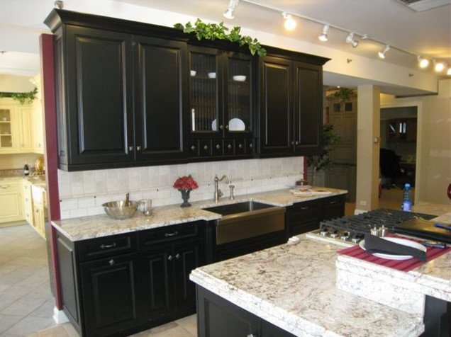 Example of a small classic galley limestone floor and gray floor eat-in kitchen design in Chicago with a farmhouse sink, raised-panel cabinets, black cabinets, stainless steel appliances, an island, granite countertops, gray backsplash and limestone backsplash