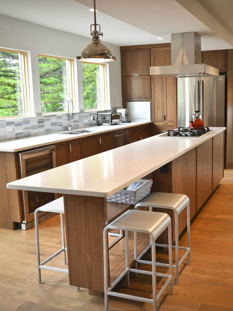 Exempel på ett modernt kök, med en dubbel diskho, luckor med infälld panel, skåp i mellenmörkt trä, bänkskiva i kvarts, rostfria vitvaror, grått stänkskydd och stänkskydd i stenkakel