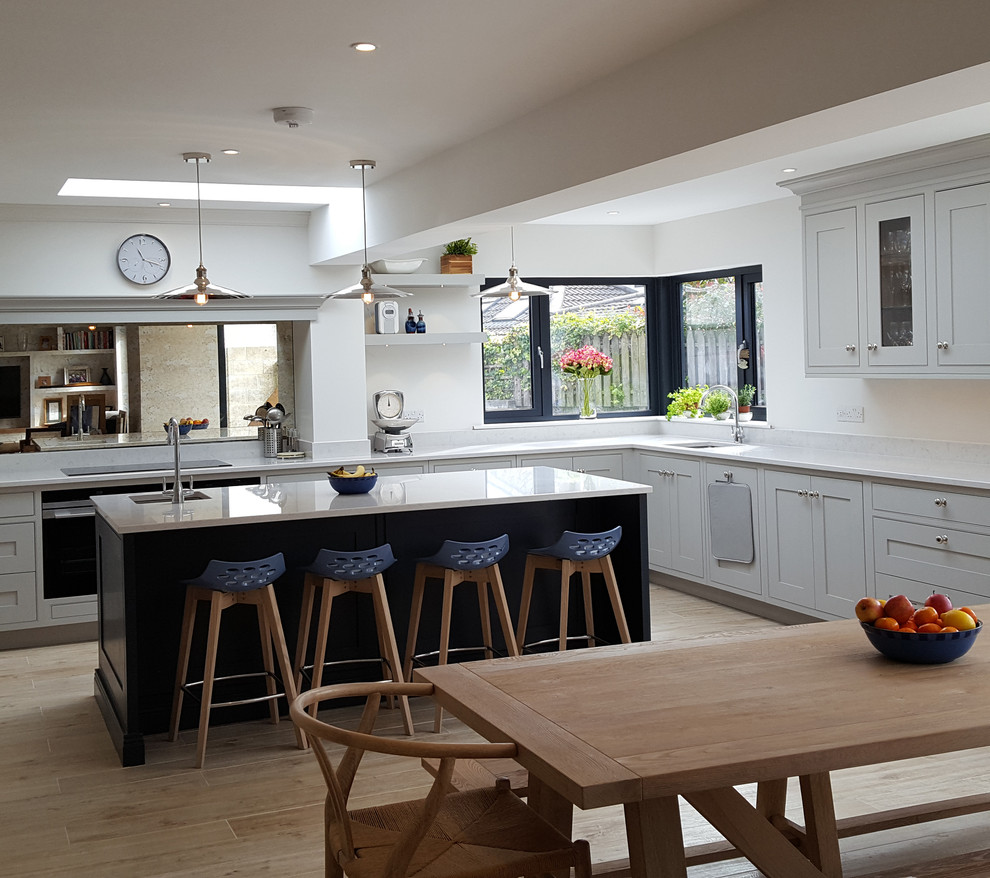 Contemporary l-shaped kitchen/diner in Dublin with a built-in sink, recessed-panel cabinets, grey cabinets, marble worktops, metallic splashback, mirror splashback, integrated appliances, porcelain flooring and an island.