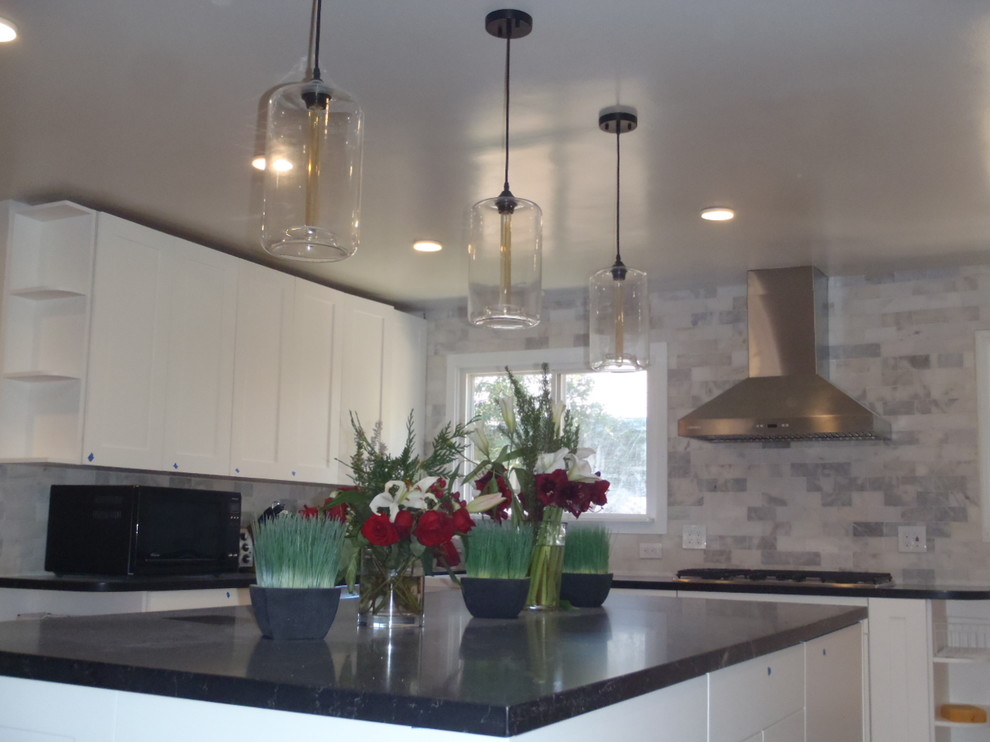 Foto på ett stort funkis kök med öppen planlösning, med skåp i shakerstil, vita skåp, grått stänkskydd, rostfria vitvaror och ljust trägolv