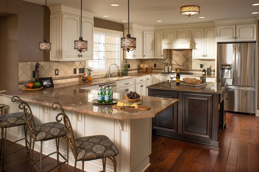 Example of a classic u-shaped medium tone wood floor open concept kitchen design in Charleston with an undermount sink, raised-panel cabinets, distressed cabinets, granite countertops, beige backsplash, porcelain backsplash and stainless steel appliances