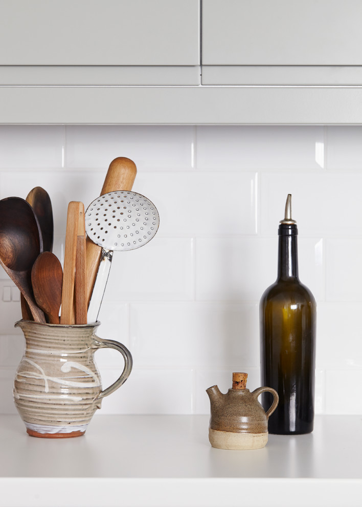 Immagine di un cucina con isola centrale contemporaneo con ante lisce, ante grigie, top in laminato, paraspruzzi bianco, paraspruzzi con piastrelle in ceramica, parquet scuro e top bianco
