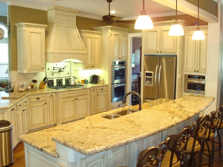 Bild på ett avskilt, mellanstort vintage l-kök, med en dubbel diskho, luckor med upphöjd panel, vita skåp, granitbänkskiva, beige stänkskydd, stänkskydd i stenkakel, rostfria vitvaror, mellanmörkt trägolv, en köksö och brunt golv