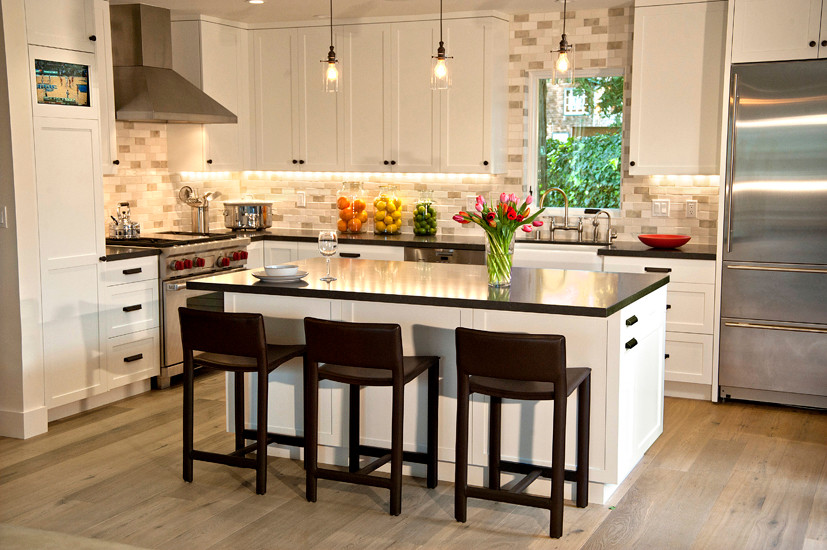 Inredning av ett modernt stort kök, med en rustik diskho, vita skåp, bänkskiva i kvarts, flerfärgad stänkskydd, rostfria vitvaror, ljust trägolv och en köksö