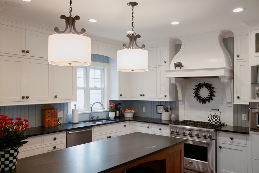 Bild på ett mellanstort lantligt l-kök, med en undermonterad diskho, skåp i shakerstil, vita skåp, granitbänkskiva, blått stänkskydd, stänkskydd i trä, rostfria vitvaror, en köksö, mellanmörkt trägolv och brunt golv