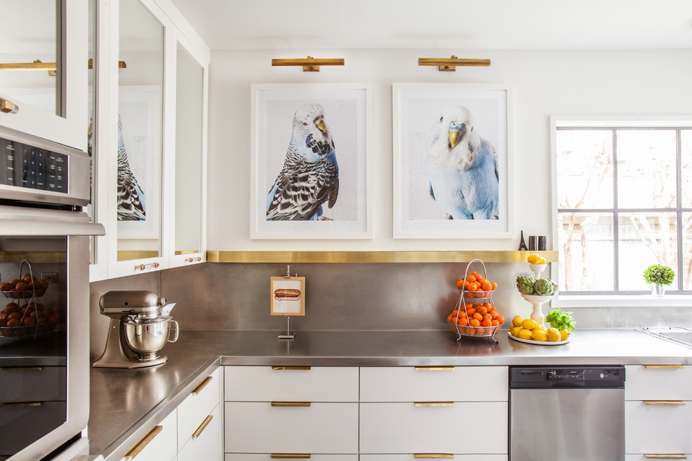 Moderne Küche mit flächenbündigen Schrankfronten, weißen Schränken, Edelstahl-Arbeitsplatte, Küchenrückwand in Metallic und Küchengeräten aus Edelstahl in Houston
