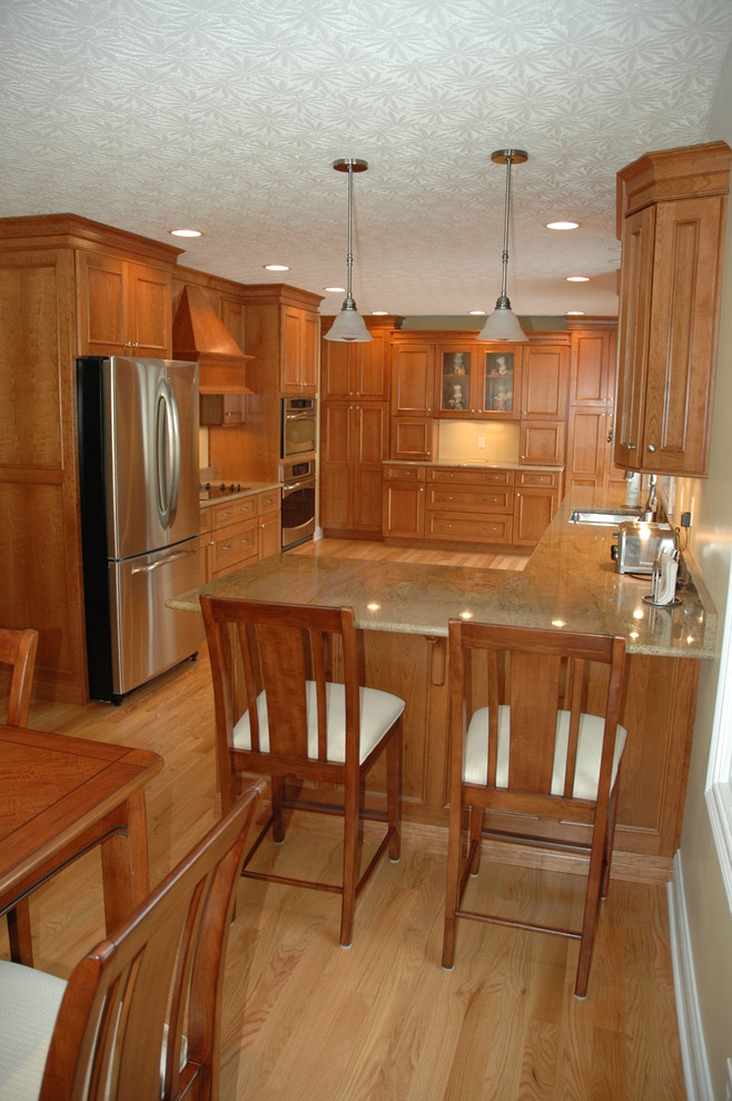 Klassisk inredning av ett mellanstort kök och matrum, med en dubbel diskho, luckor med infälld panel, skåp i mellenmörkt trä, rostfria vitvaror, mellanmörkt trägolv och en halv köksö
