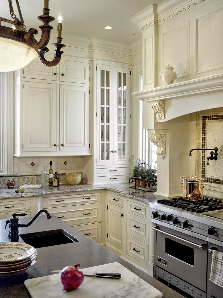 Example of a classic kitchen design in Philadelphia with granite countertops, stainless steel appliances, an undermount sink, raised-panel cabinets, beige cabinets, multicolored backsplash and limestone backsplash