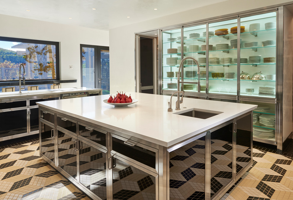 Immagine di un cucina con isola centrale design con ante di vetro e ante in acciaio inossidabile