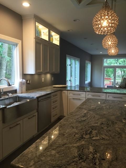This is an example of a large shabby-chic style u-shaped kitchen/diner in Philadelphia with a belfast sink, glass-front cabinets, white cabinets, granite worktops, porcelain splashback, stainless steel appliances, porcelain flooring and a breakfast bar.