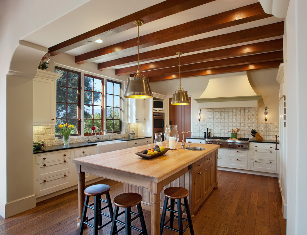 Exempel på ett mellanstort medelhavsstil kök, med en rustik diskho, vita skåp, träbänkskiva, integrerade vitvaror, mellanmörkt trägolv, en köksö, skåp i shakerstil, flerfärgad stänkskydd och orange golv