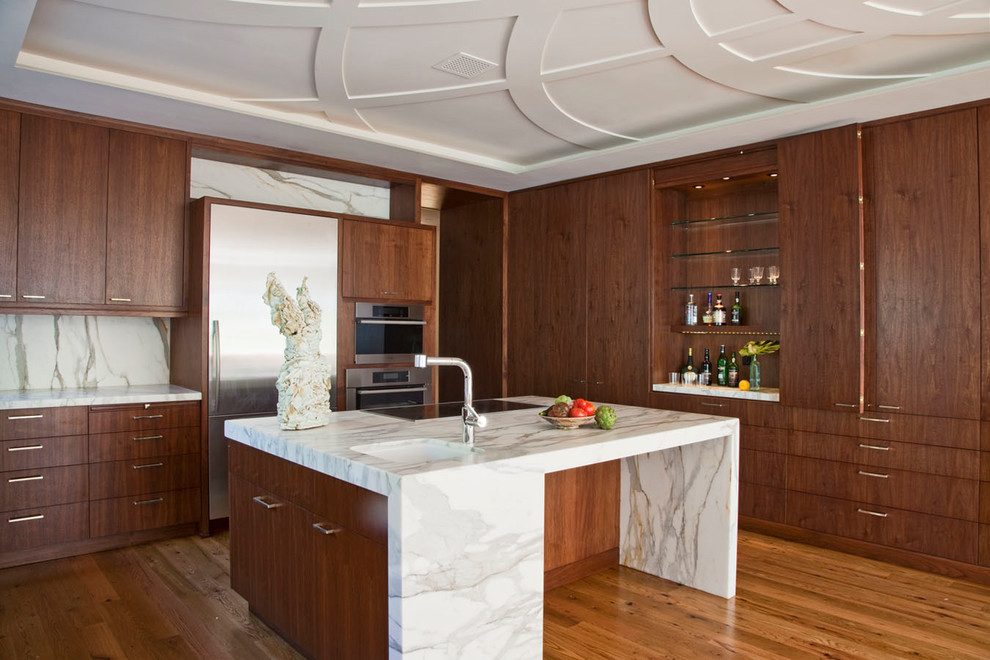 Mid-sized trendy medium tone wood floor and beige floor kitchen photo in Santa Barbara with flat-panel cabinets, marble countertops, white backsplash, marble backsplash, stainless steel appliances, an island, an undermount sink and dark wood cabinets