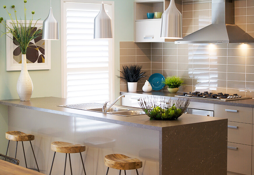 Modern inredning av ett litet linjärt kök, med en dubbel diskho, släta luckor, bruna skåp, granitbänkskiva, brunt stänkskydd, stänkskydd i porslinskakel, rostfria vitvaror och en köksö