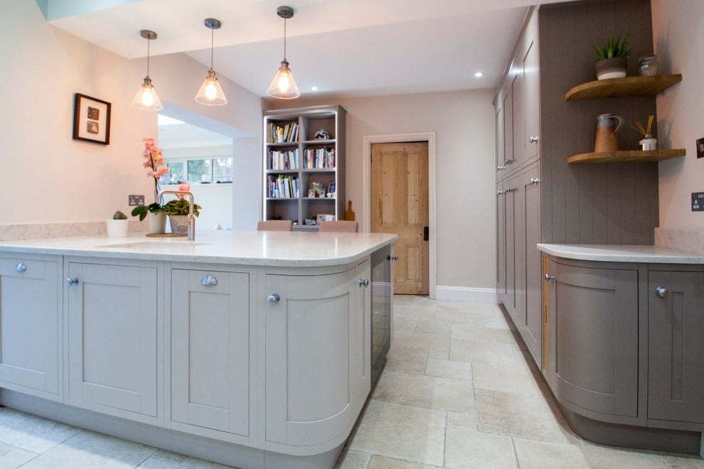 Large traditional u-shaped open plan kitchen in Hampshire with a built-in sink, shaker cabinets, grey cabinets, quartz worktops, blue splashback, ceramic splashback, integrated appliances, ceramic flooring, an island and beige floors.