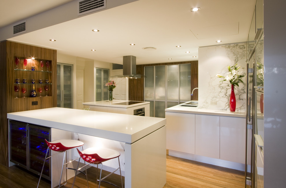 Contemporary kitchen in Brisbane with stainless steel appliances, glass-front cabinets, white cabinets, white splashback and stone slab splashback.
