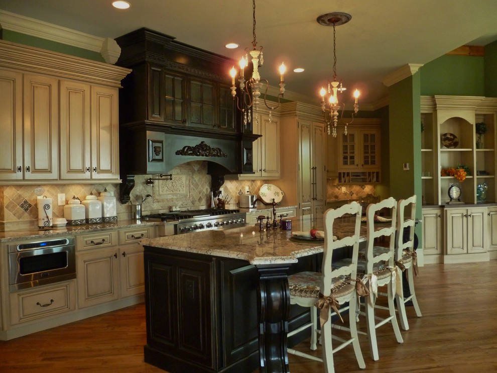 Kitchen - mid-sized craftsman single-wall medium tone wood floor and brown floor kitchen idea in Atlanta with recessed-panel cabinets, distressed cabinets, granite countertops, multicolored backsplash, ceramic backsplash, paneled appliances and an island