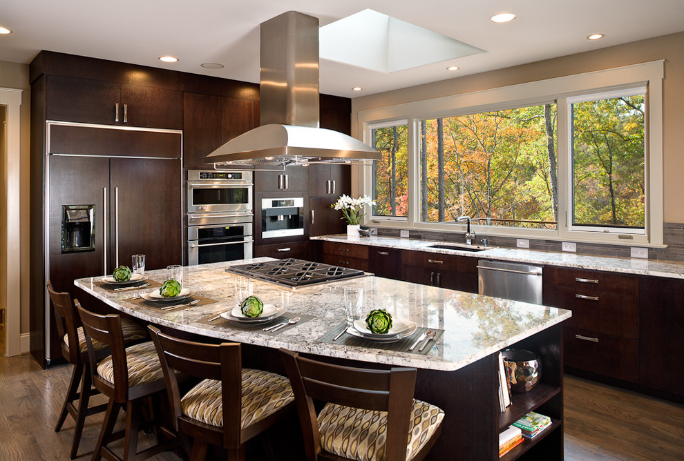 Moderne Küchenbar in L-Form mit Granit-Arbeitsplatte, flächenbündigen Schrankfronten, dunklen Holzschränken, Küchenrückwand in Grau und Küchengeräten aus Edelstahl in Sonstige