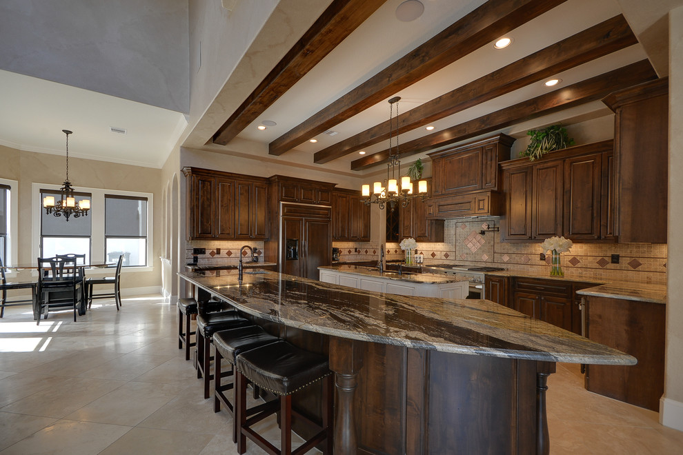 Inspiration for a large rustic u-shaped travertine floor and beige floor open concept kitchen remodel in Houston with an undermount sink, raised-panel cabinets, dark wood cabinets, granite countertops, beige backsplash, ceramic backsplash, paneled appliances and two islands