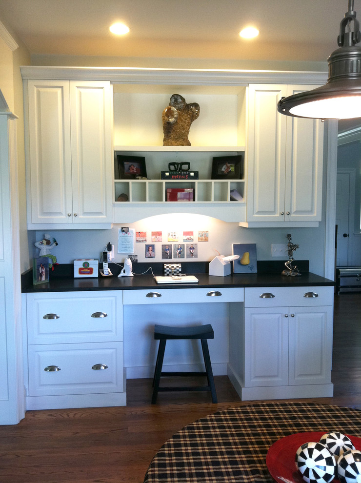 Example of a classic medium tone wood floor and brown floor kitchen design in Boston with raised-panel cabinets, white cabinets, granite countertops, gray backsplash and black countertops