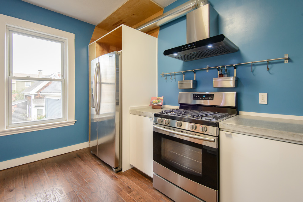 Medium sized contemporary galley enclosed kitchen in Boston with a built-in sink, flat-panel cabinets, white cabinets, concrete worktops, blue splashback, stainless steel appliances, dark hardwood flooring, no island and brown floors.