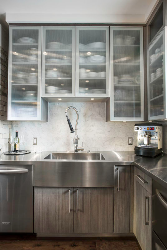 Inspiration for a modern kitchen in Salt Lake City with a built-in sink, glass-front cabinets, stainless steel worktops, white splashback and stainless steel appliances.